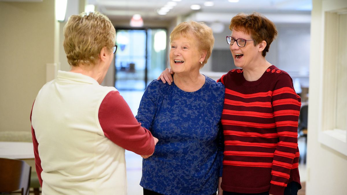 Three residents greeting each other in common area at Cedar Community